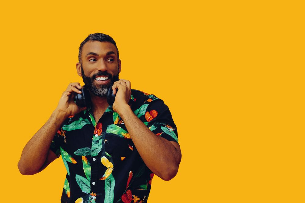 Black male in bold patterned shirt and headphones in yellow room