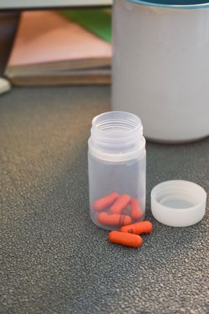 Red pills in container on counter