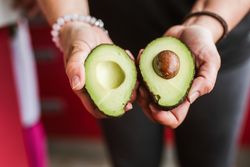 Crop woman showing cut avocado