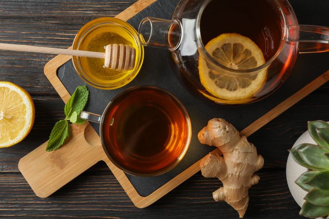 Cup of tea, mint, honey, ginger and teapot on wooden background, top view