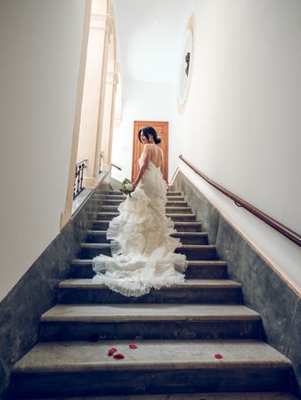 Bride in white dress with frills and lace walking upstairs
