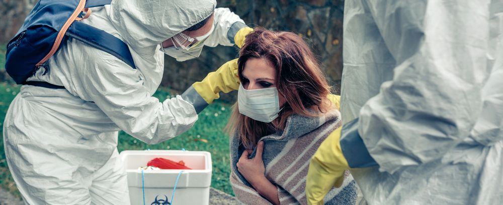 Doctors putting protective mask on woman infected with a virus