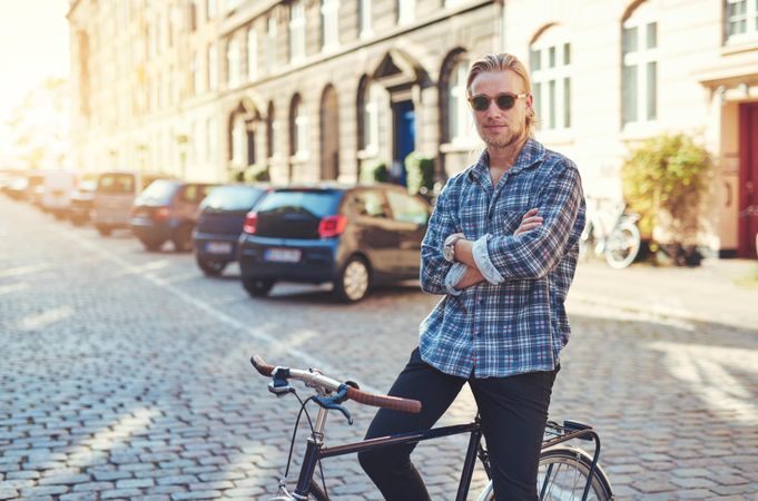 Man in sunglasses on cobble street sitting on bike
