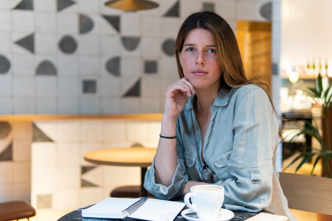Dreamy woman with notebook and tea in cafe