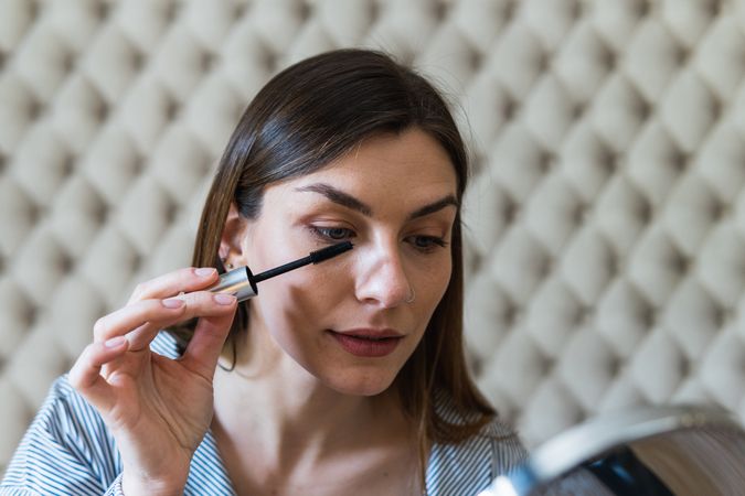 Woman applying mascara on eyelashes