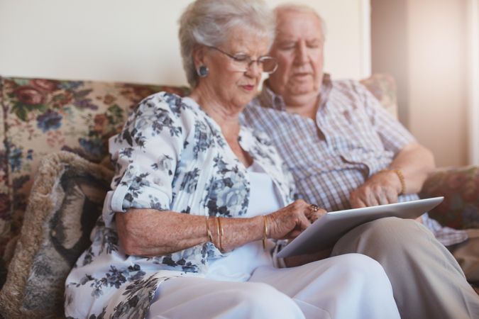 Portrait of older woman sitting with her husband and using digital tablet