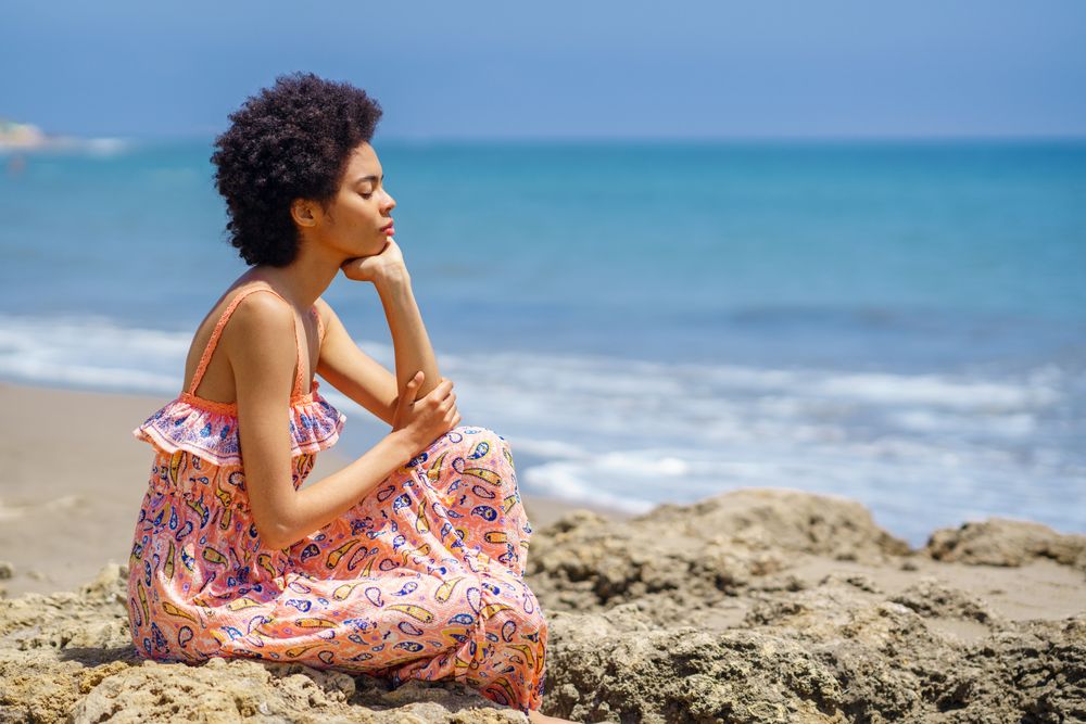 Woman sitting on the rocks on the coast facing the ocean view