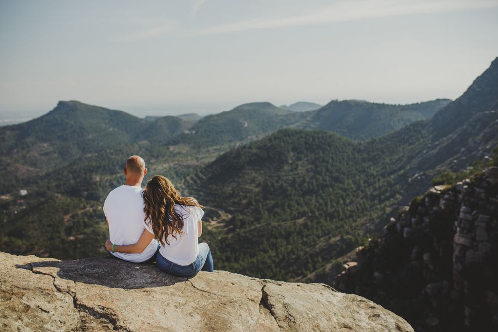 Happy couple sitting at mountain cliff