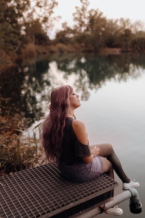 Stylish modern woman sitting on metal pier