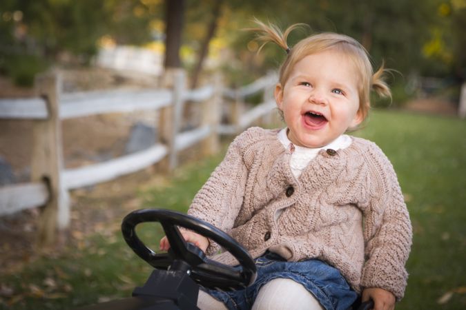 Young Toddler Laughing and Playing on Toy Tractor Outside