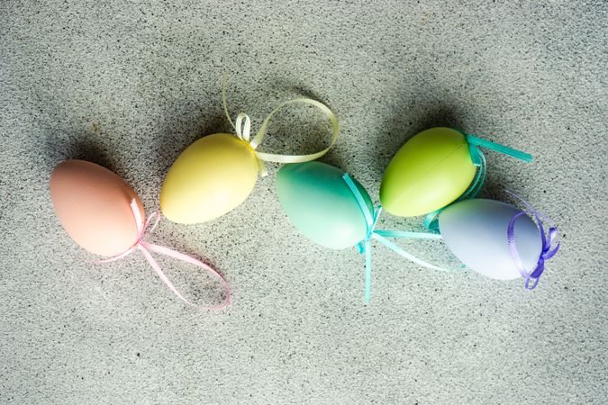 Easter card concept with line of pastel egg ornaments scattered on concrete table
