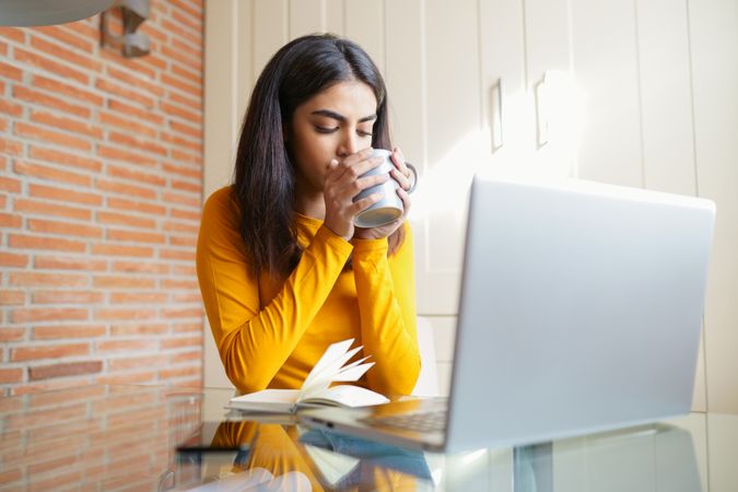 Woman sipping coffee while working from home
