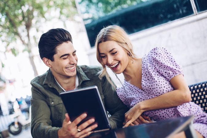 Happy young couple using tablet outdoors