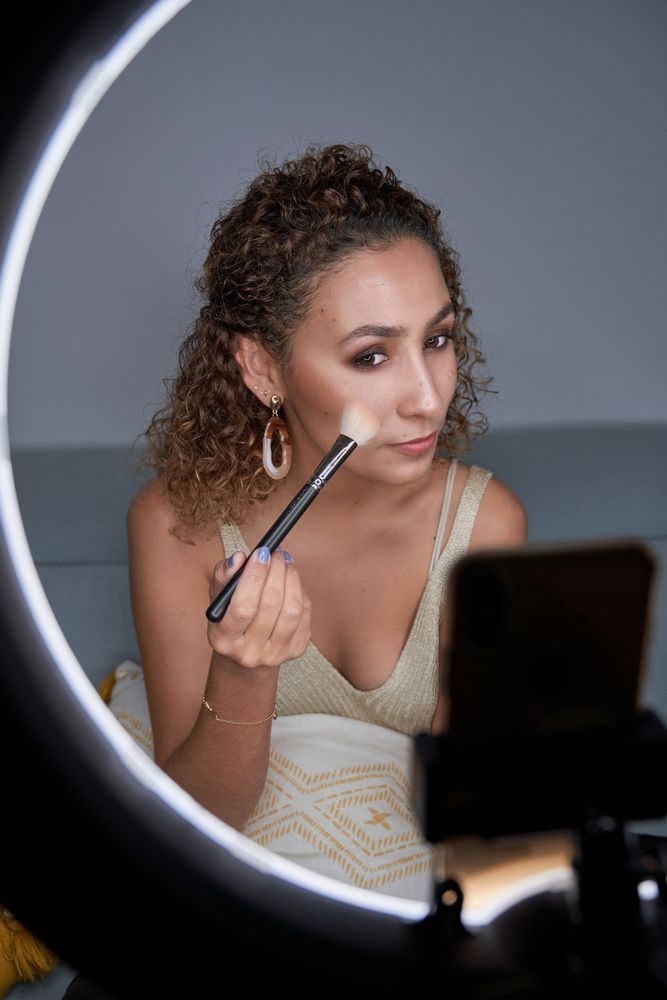 Focused female visagiste shading blush with brush on cheek