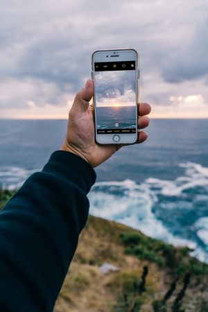 Person taking photo of cliffs and sea
