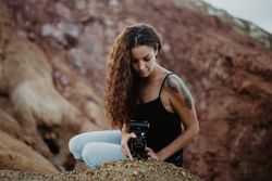 Woman with camera sitting on cliff