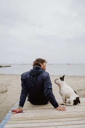 Man and dog resting on beach together