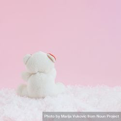 Back of plush bear sitting in snow in pink room bY9wDb