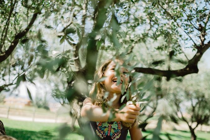 Smiling girl climbing tree in sunny day