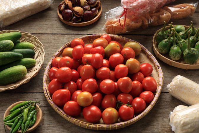 Fresh Red Small Tomato on Woven Bamboo Tray Above Wooden Table
