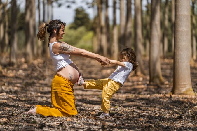 Pregnant mother and little daughter having fun in park