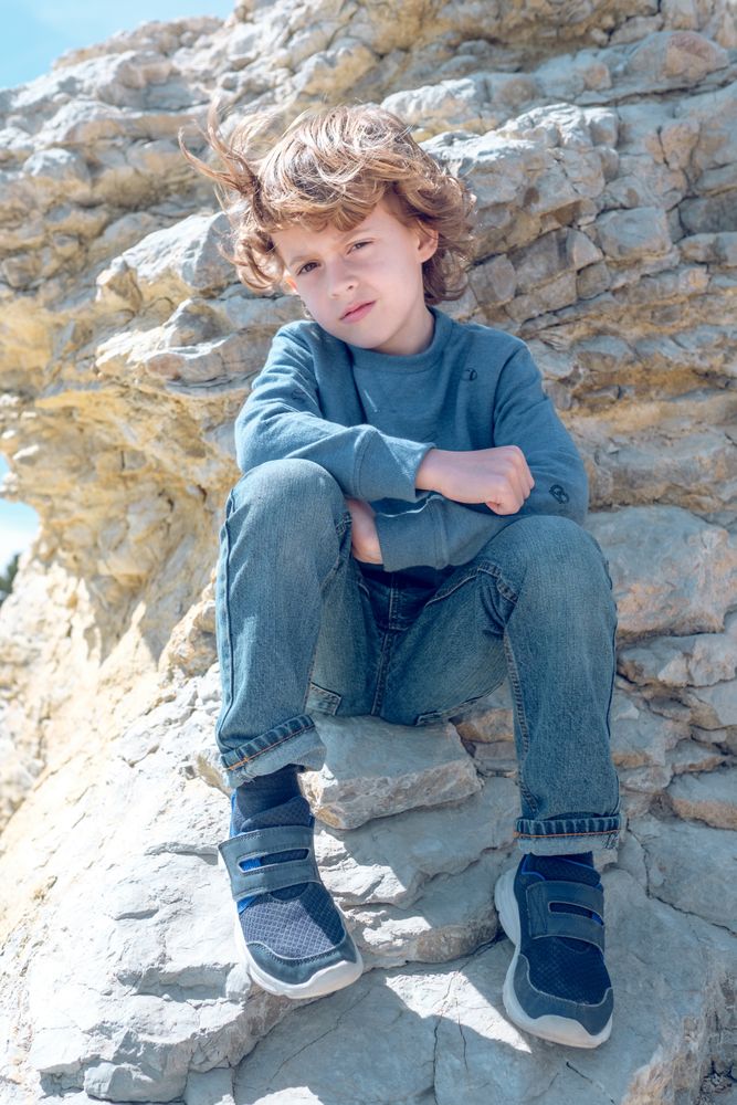 Calm boy sitting on cliff
