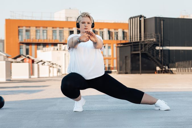 Curvy woman stretching ahead of her workout on a rooftop