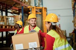 Positive warehouse workers carrying heavy box