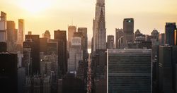 Beautiful Cinematic Aerial Sunset Shot of New York City Skyscrapers and Busy City Streets with Car Traffic. Panoramic Helicopter View of Lower Manhattan Office Buildings