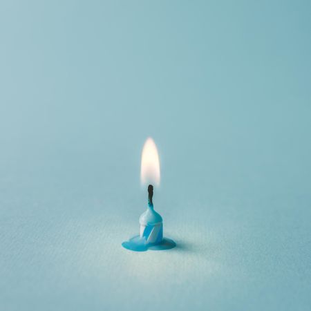 Lit blue candle on blue background