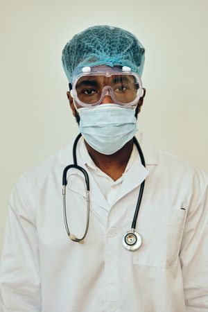 Closeup portrait of Black male doctor in bright studio with full ppe gear ready for surgery