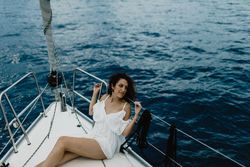 Barefoot bride resting on yacht bow