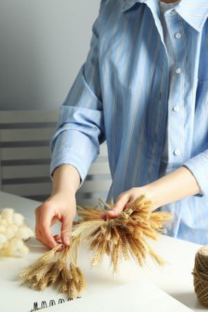 Woman in blue striped shirt arranging dried flowers, vertical