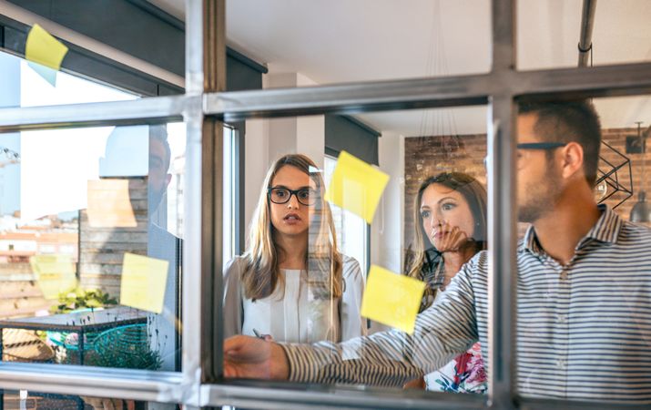 Business people in a work meeting placing sticky notes on the wall