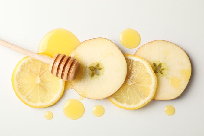 Dipper, honey, apple and lemon slices on blank background, top view