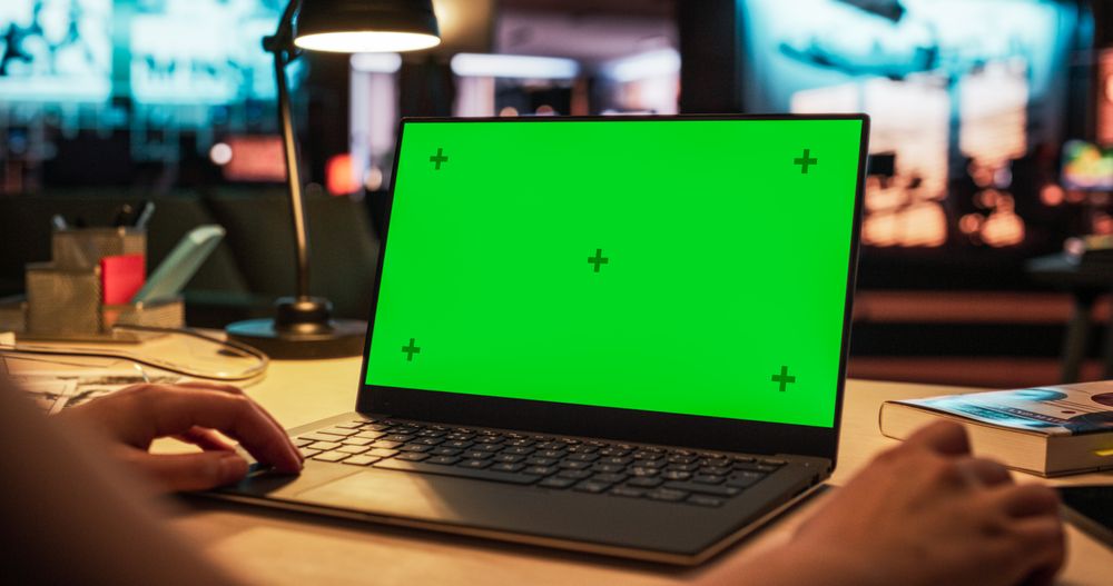 Anonymous Designer Working on a Laptop Computer with Mock Up Green Screen Chromakey Display with Isolated Placeholder. Video Template for Artistic Content Creation and Presentations