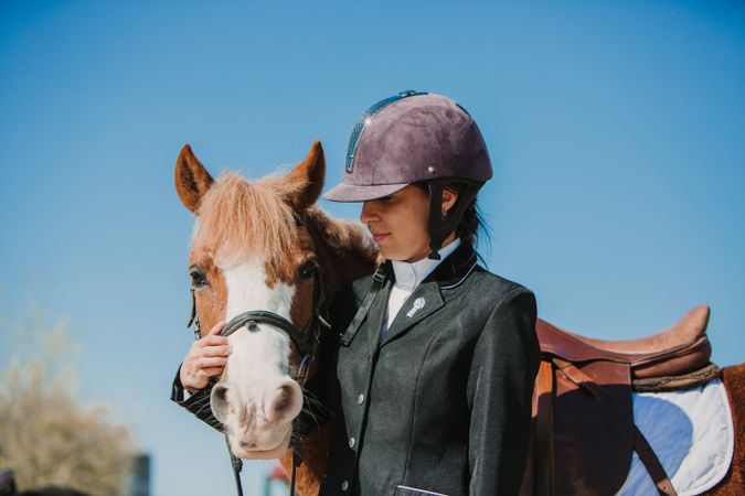 Woman in jockey outfit standing with horse