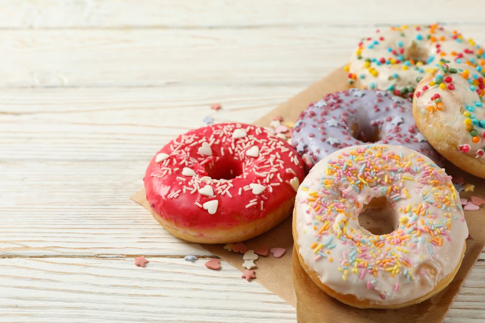 Baking paper with donuts on wooden background, close up