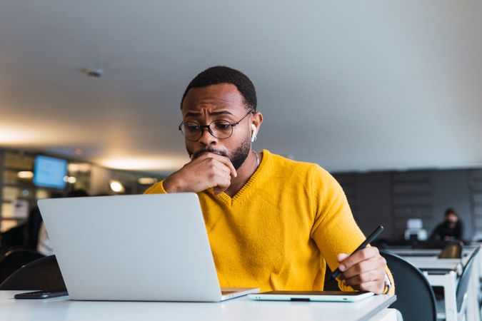 Black man working on laptop with tablet