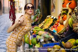 Glamorous woman leaning over fresh fruit in outdoor market 5aXyRd