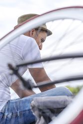 Male in hat shot through bicycle wheel