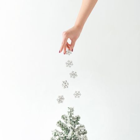 Hand sprinkling snowflakes on tree