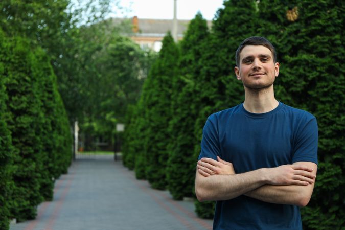 Young man in a blank t-shirt stands with folded hands