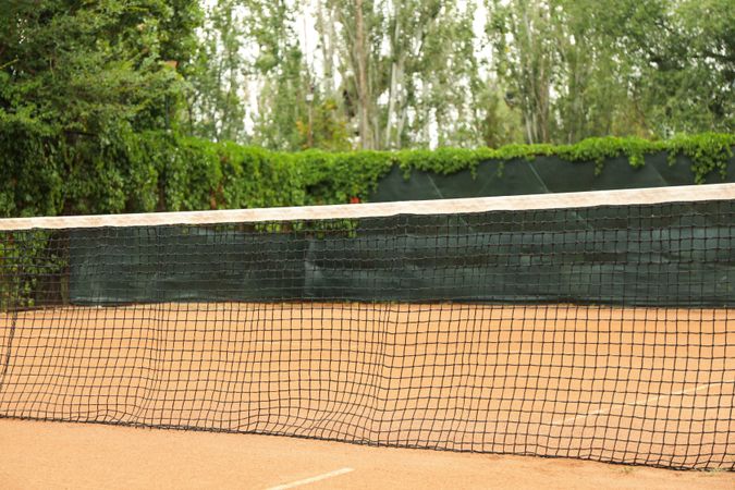 Clay tennis court with net, space for text