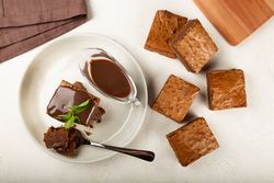 Top view of brownies and spoon served with sauce and mint garnish