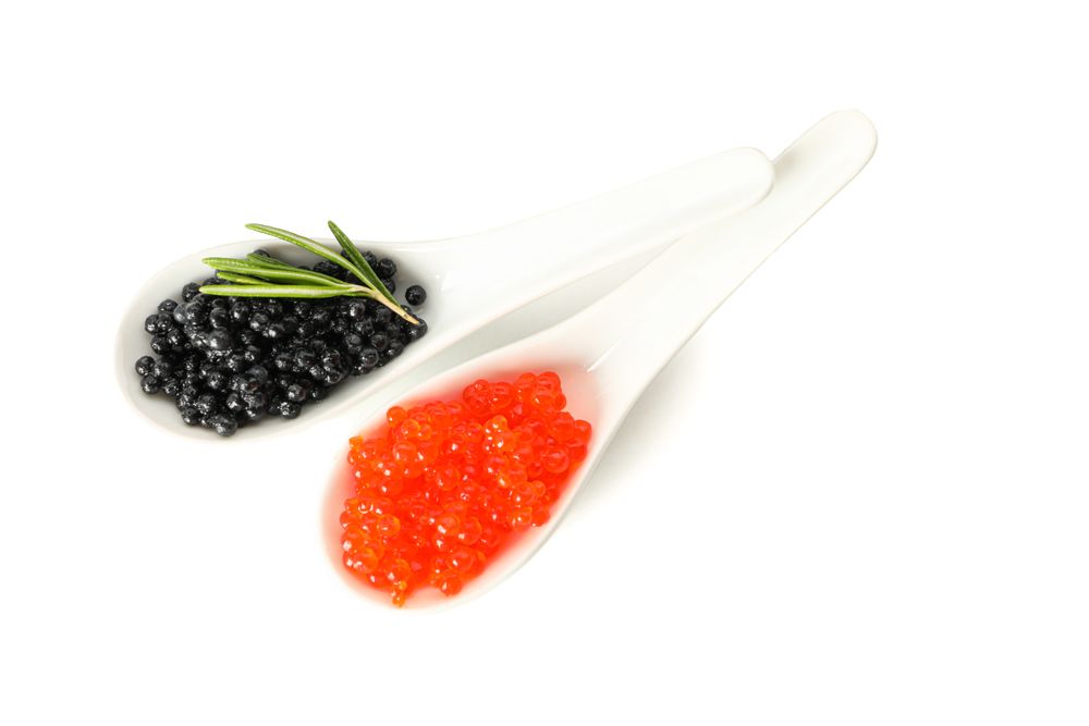 Glass spoons with caviar isolated on plain background