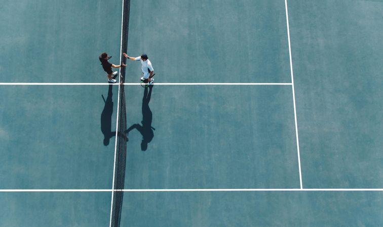 Aerial shot of professional tennis players handshakes at the net