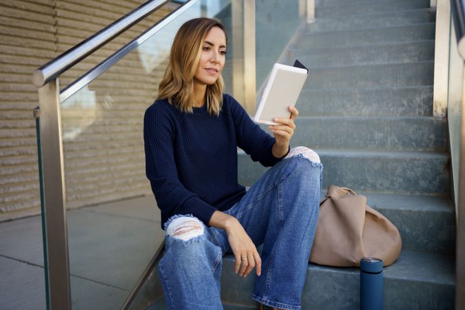 Chic woman reading e book on steps