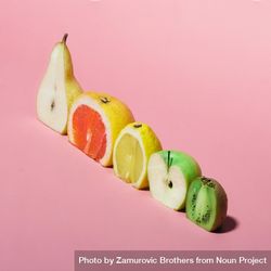 Various fruits sliced in half showing cross-section on pastel pink background 4NMmA5