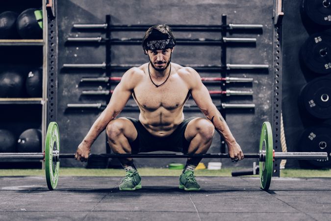 strong and athletic man doing barbell workout in modern gym